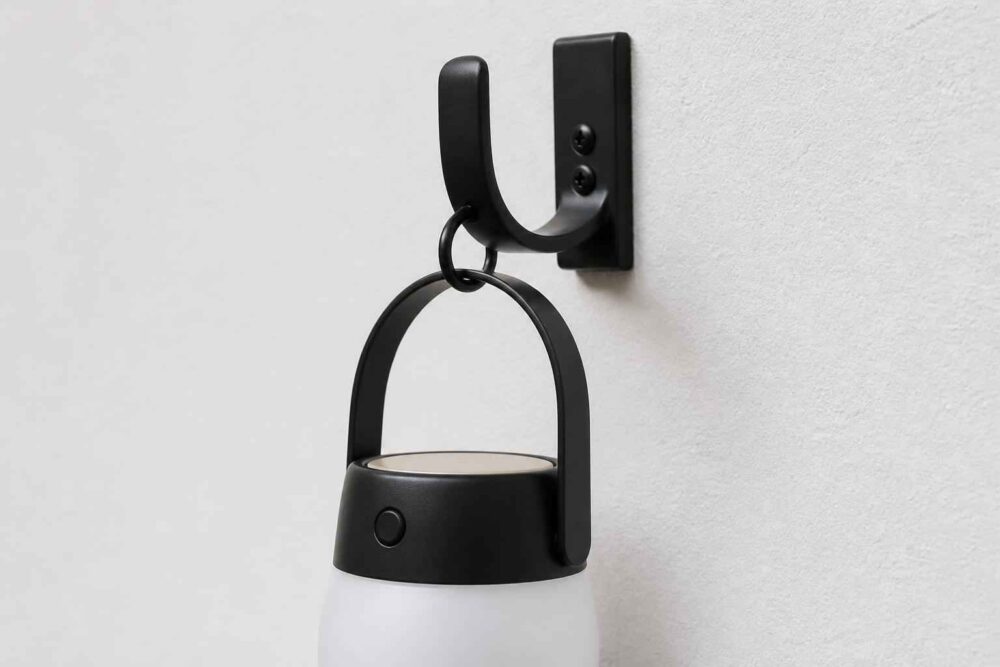 Czarna lampa wisząca zamocowana na ściennym uchwycie na jasnej ścianie
