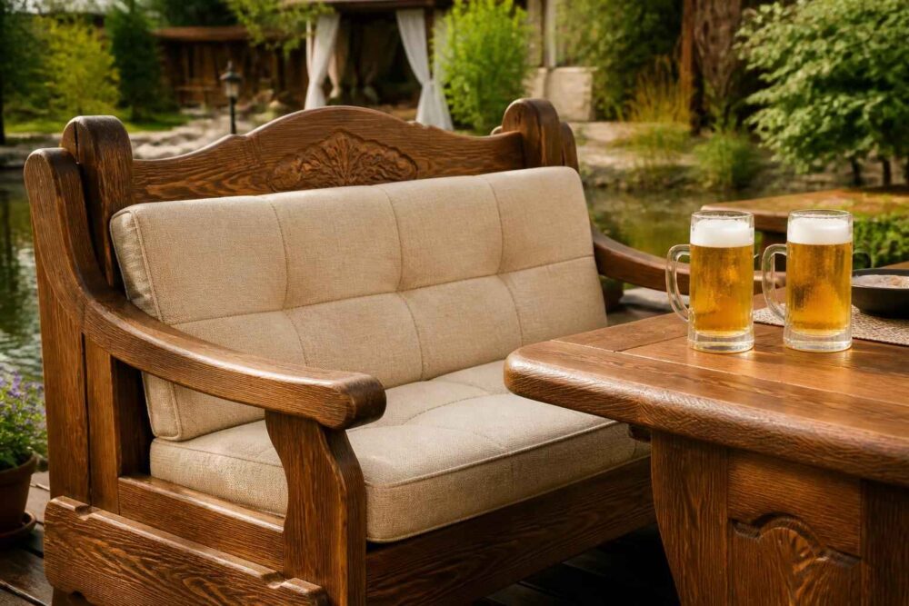 Drewniana sofa ogrodowa z jasnymi poduszkami i piwem Drewniana sofa z beżowymi poduszkami i dwoma kuflami piwa przy ogrodowym stole