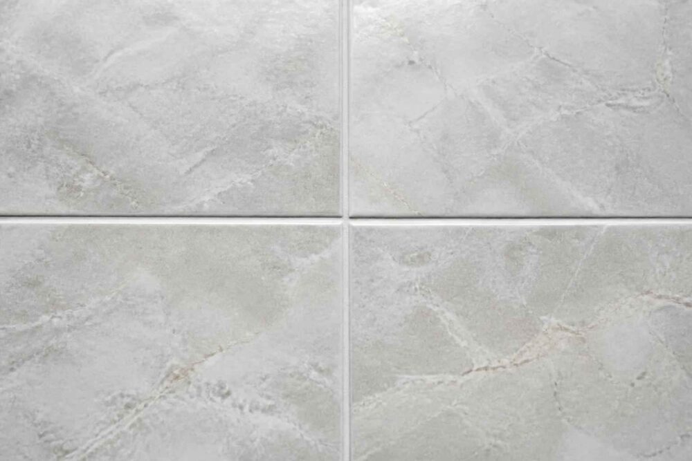 Jasnoszare płytki ceramiczne z delikatnym wzorem kamienia i widocznymi fugami